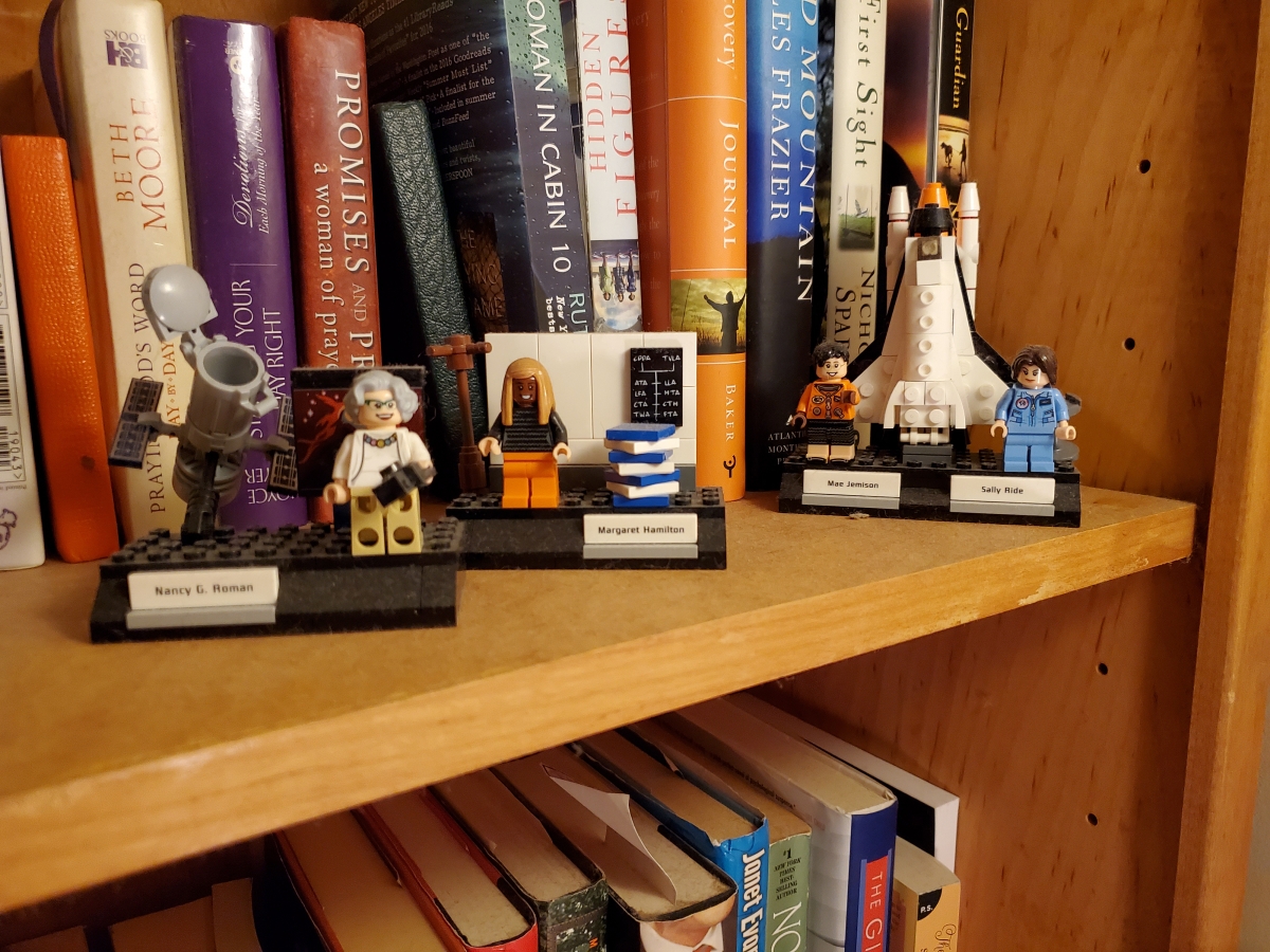 Lego figurines of famous figures line a bookcase.