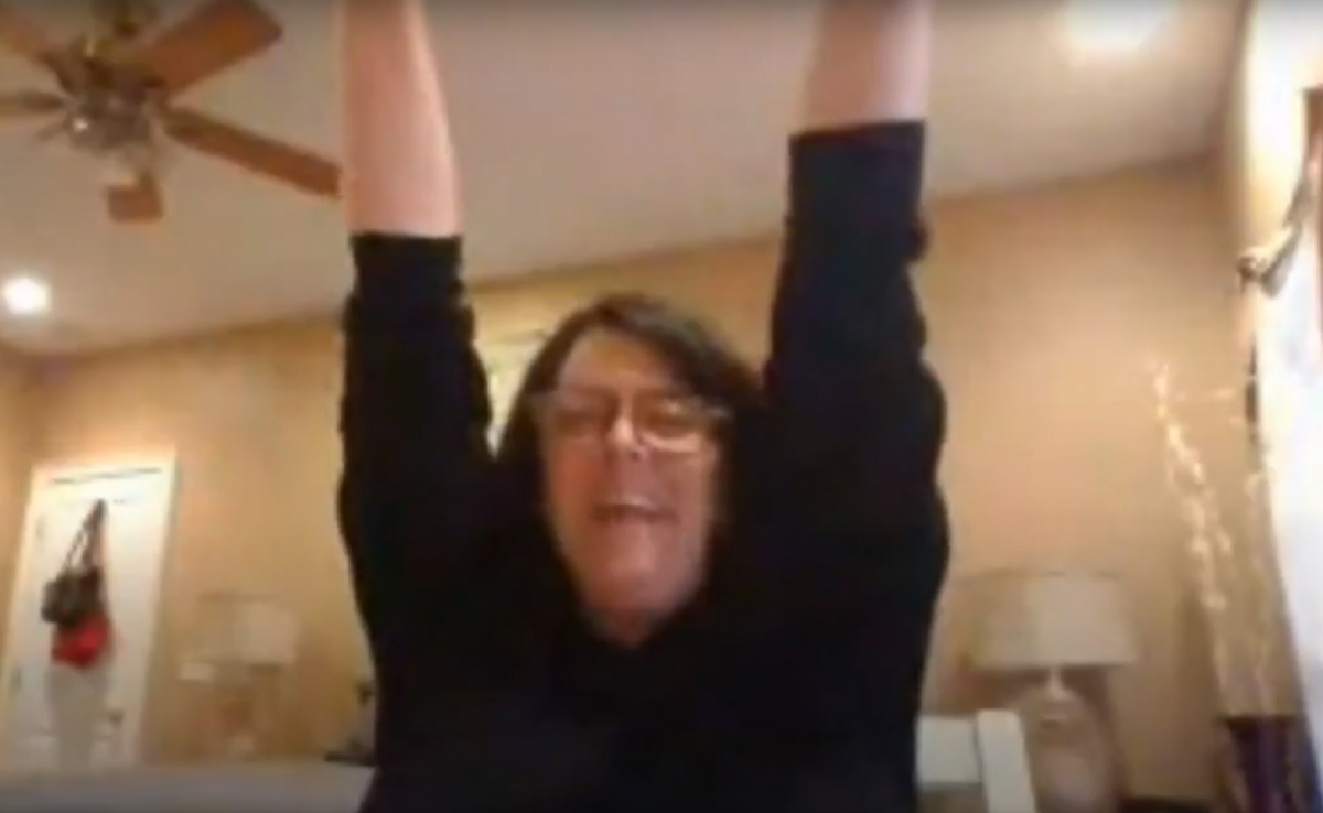Woman raises her arms in celebration in a grainy online photo