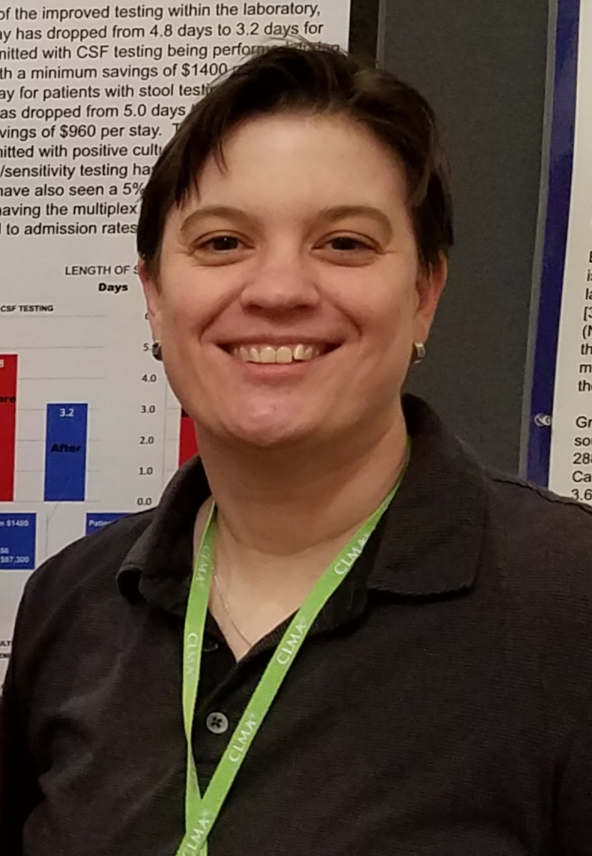 A woman smiles in front of a healthcare research poster