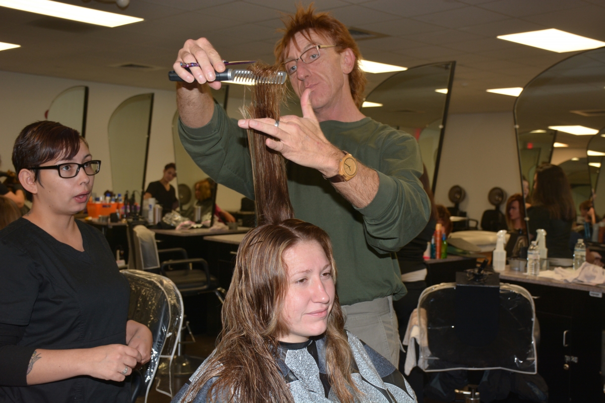 Man combs through woman's hair in SCC's cosmetology lab.