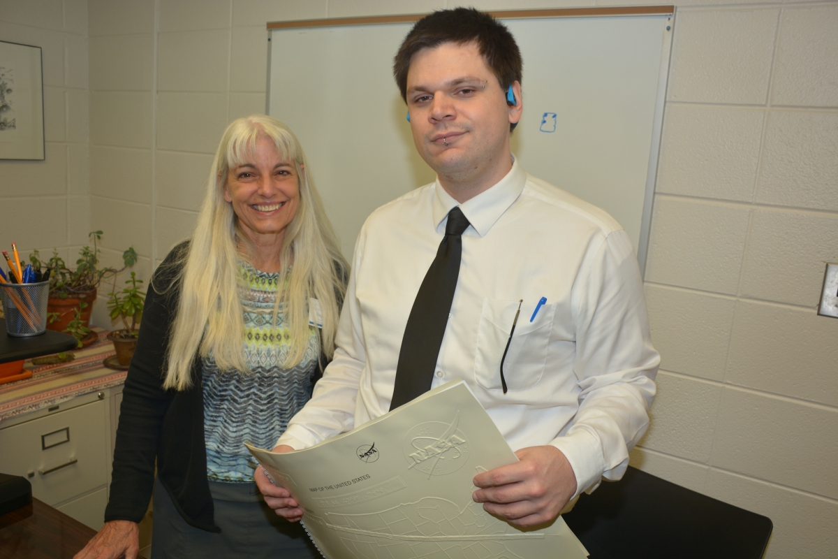A man and a woman pose with a braille book