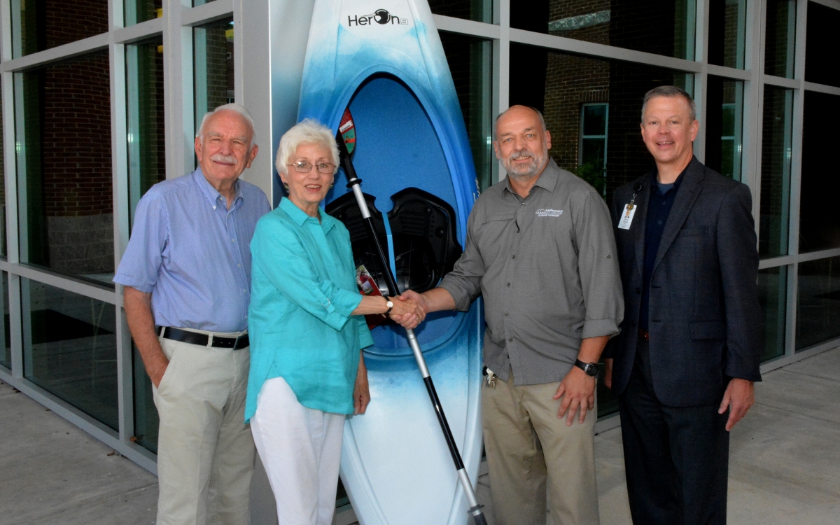 Three men and a woman stand beside a kayak outside a building on SCC's Jackson Campus.