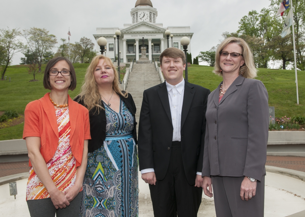 Three students, dressed professionally, stand beside their professor in front of the historic Jackson County Courthouse in Sylva, N.C.