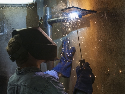 A welding student produces an arc while working on a project