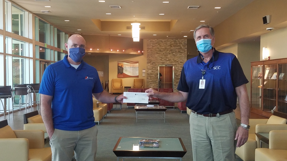 Two gentlemen shake hands while wearing masks and standing apart