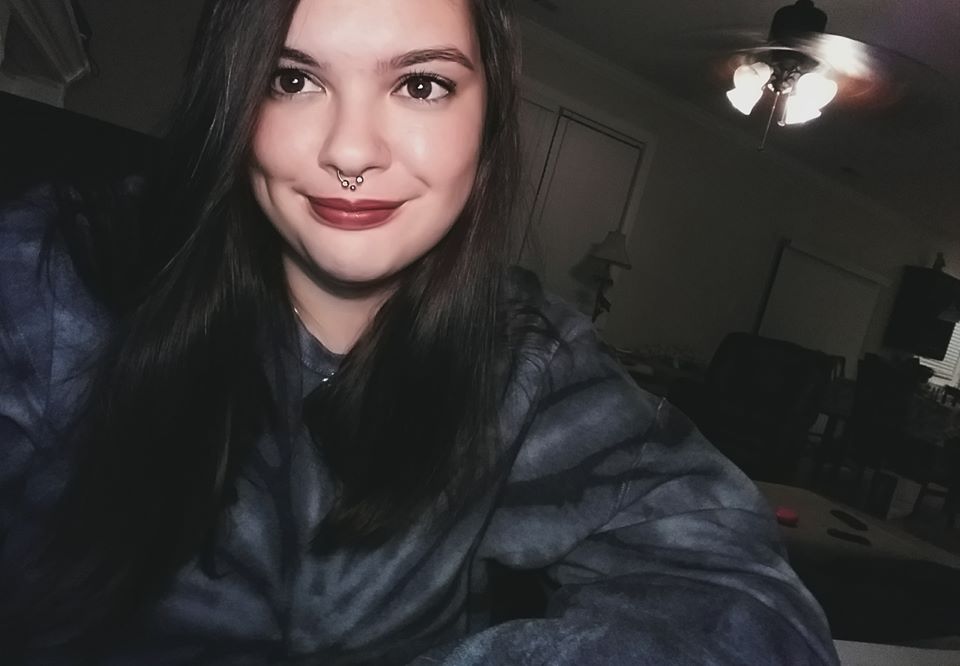 Young woman with dark hair and red lipstick smiles for a selfie