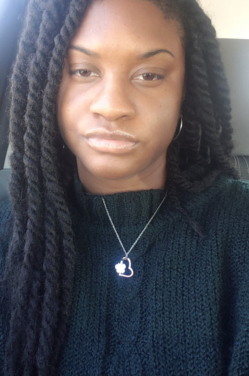 A young woman in a navy sweater smiles in a selfie.