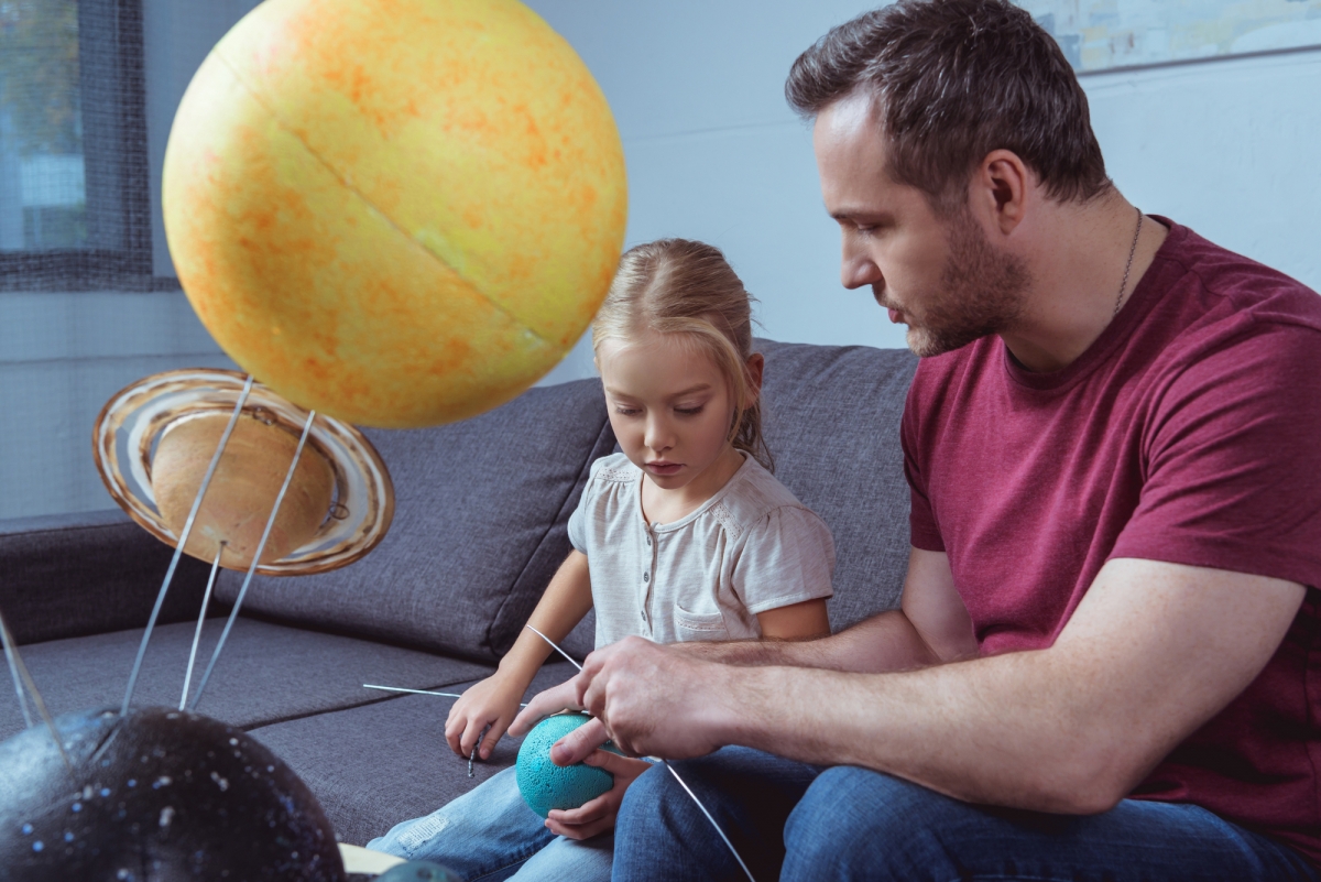 A father and his daughter build a display of planets for a science class