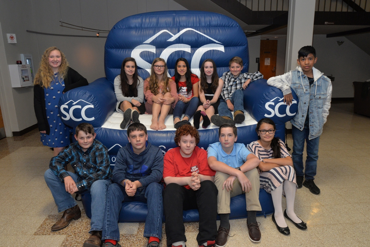 A group of young students smile while sitting on a large inflatable chair