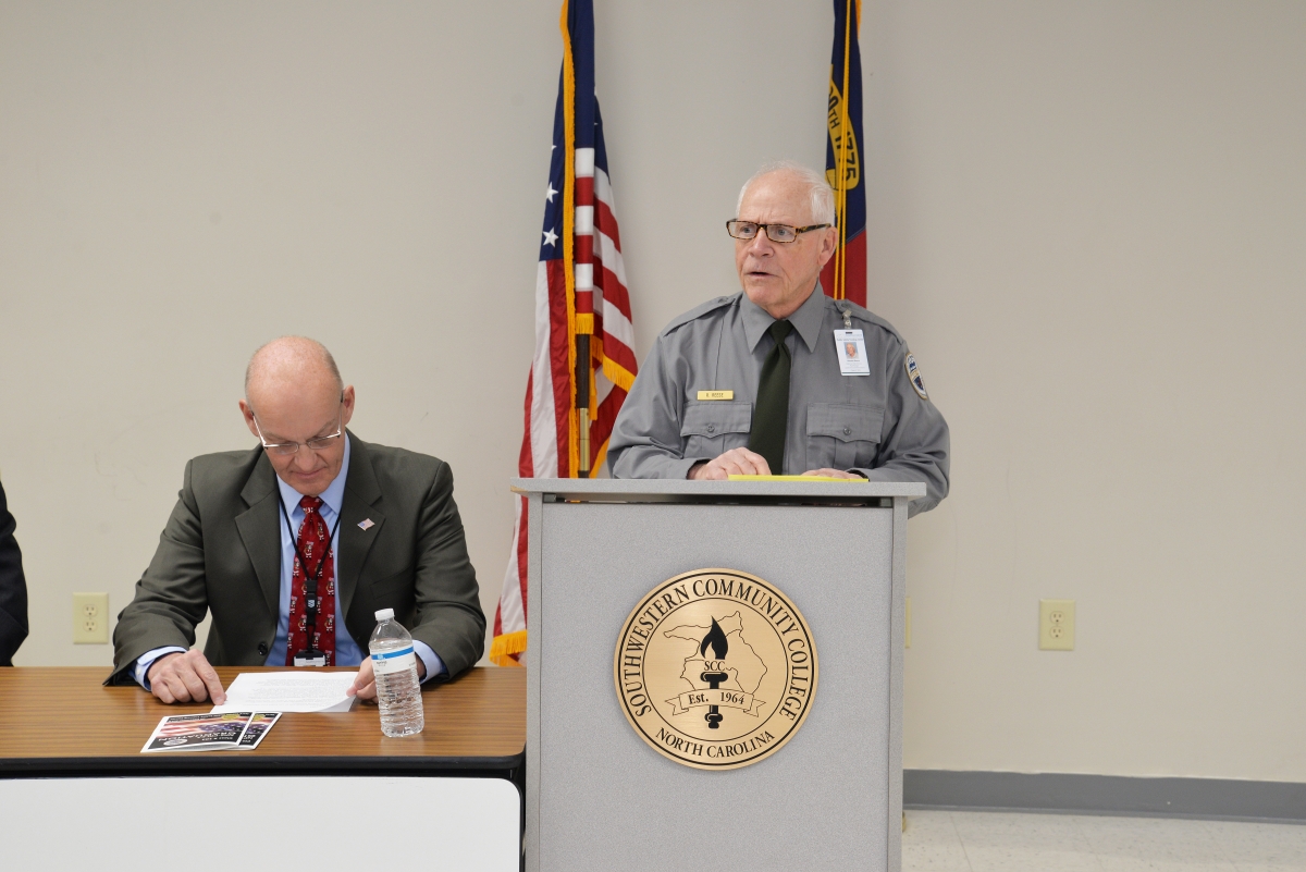 An older gentleman leans on a podium while giving a speech.