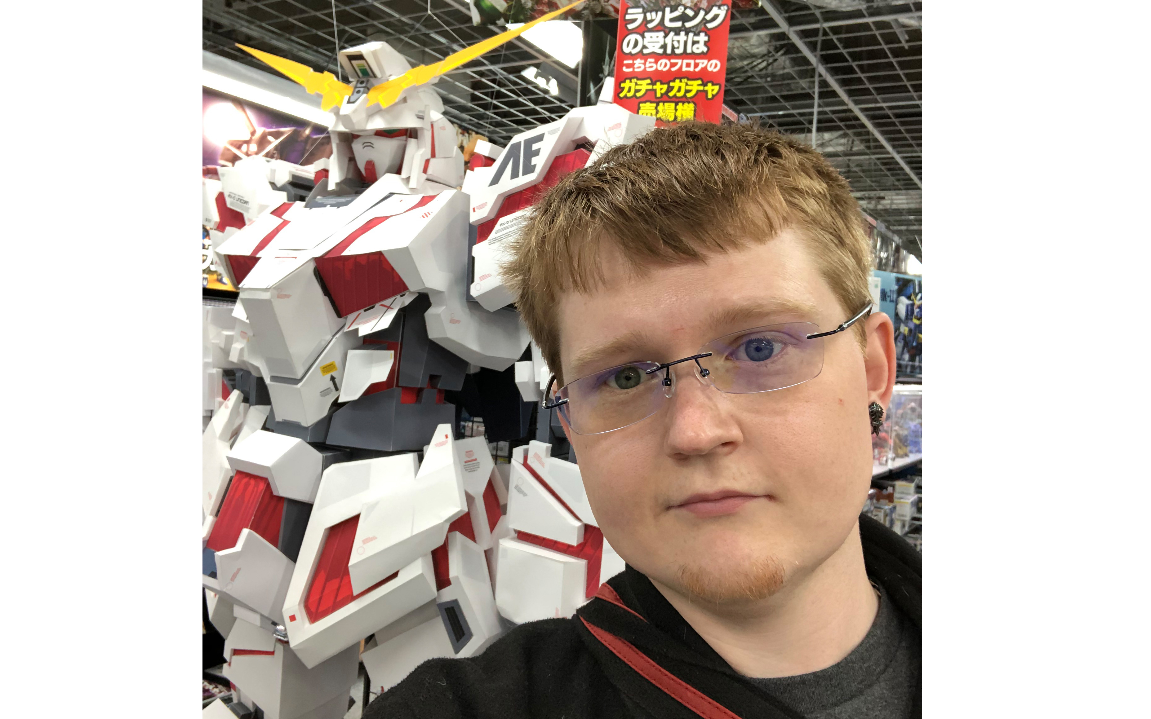 Man stands in front of robot; banner with text in Japanese language is in background