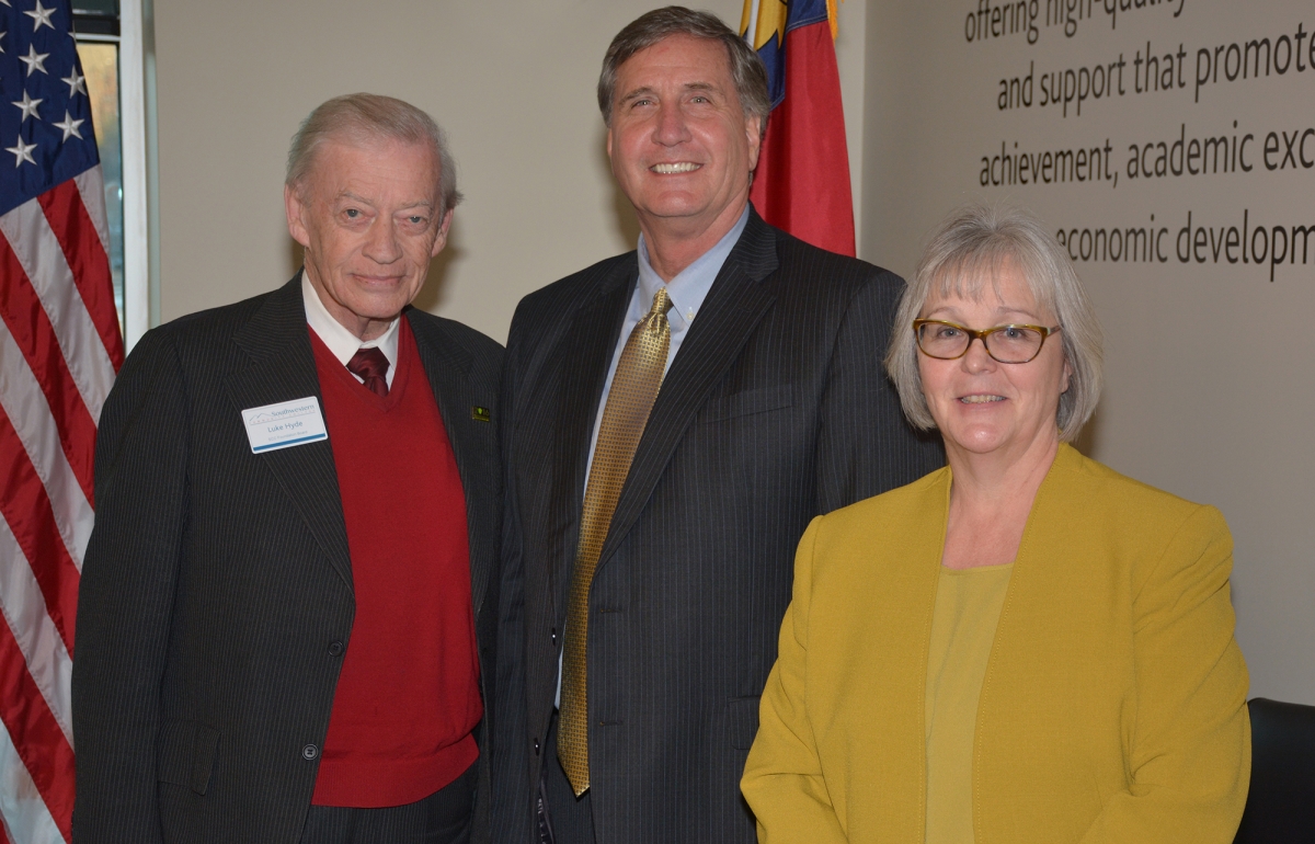 Two men and a woman pose in front of a U.S. flag inside a building on SCC's Jackson Campus.