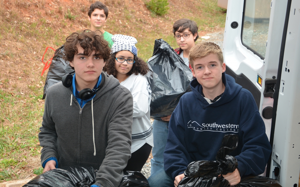 Five students load large donation-filled bags into a van.