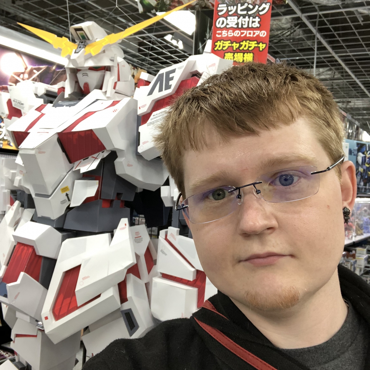 Man stands in front of robot; banner with text in Japanese language is in background