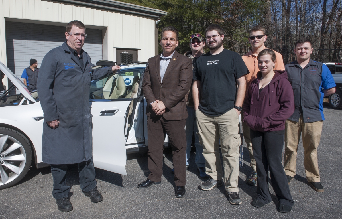 Vice Chief Richie Sneed stands with an SCC instructor and students beside his Tesla vehicle.