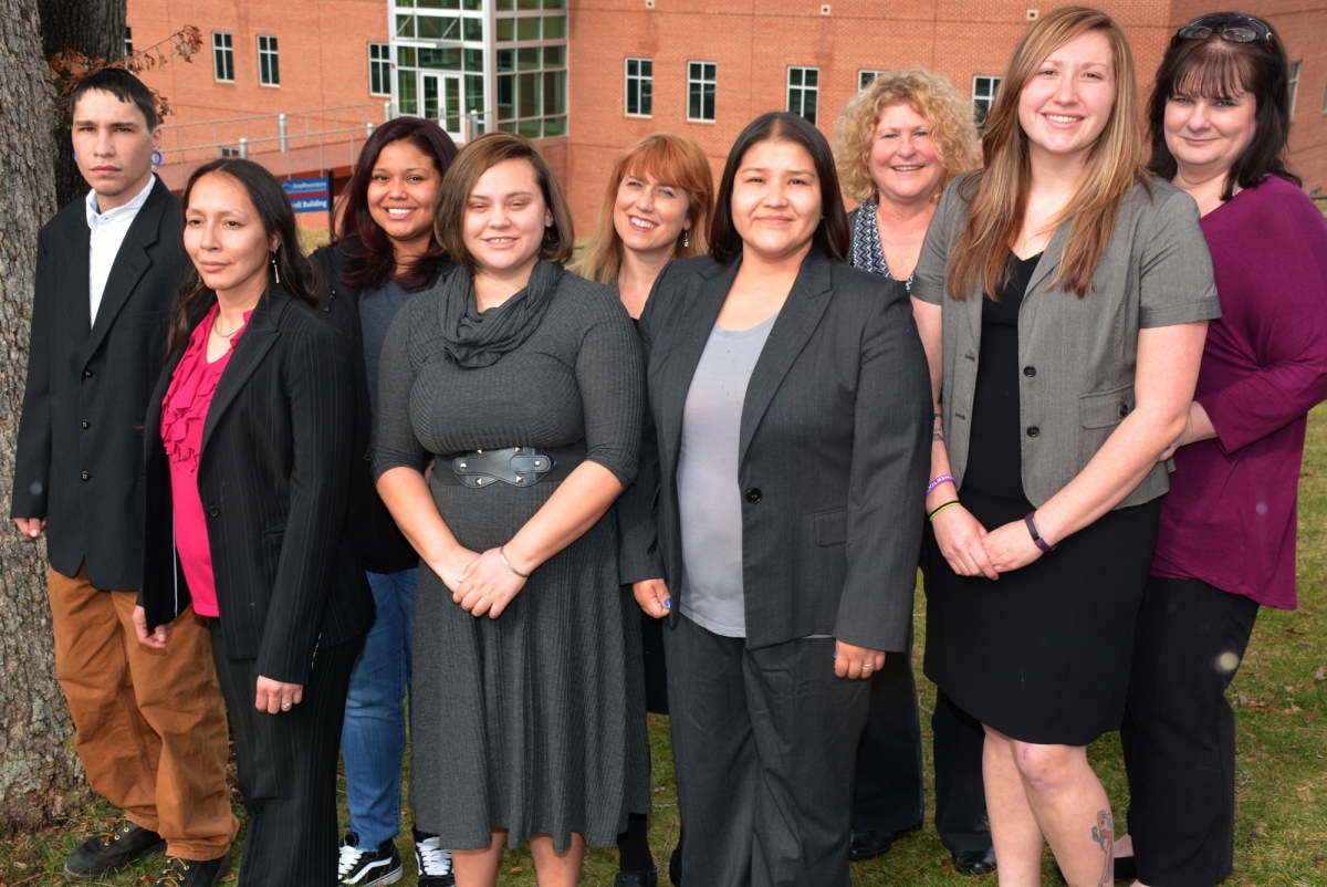 Six students and their instructors, all dressed professionally, stand outdoors with SCC's Burrell Building in the background