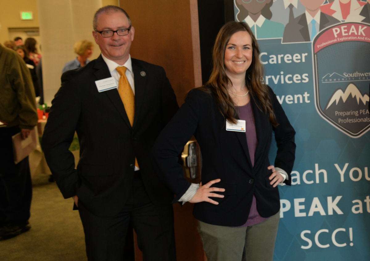 Man and woman stand at welcome table during a recent Job Fair.