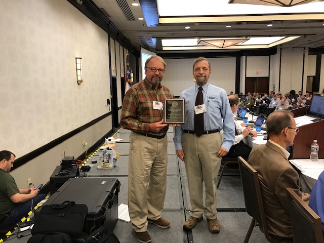 One man presents a plaque to another