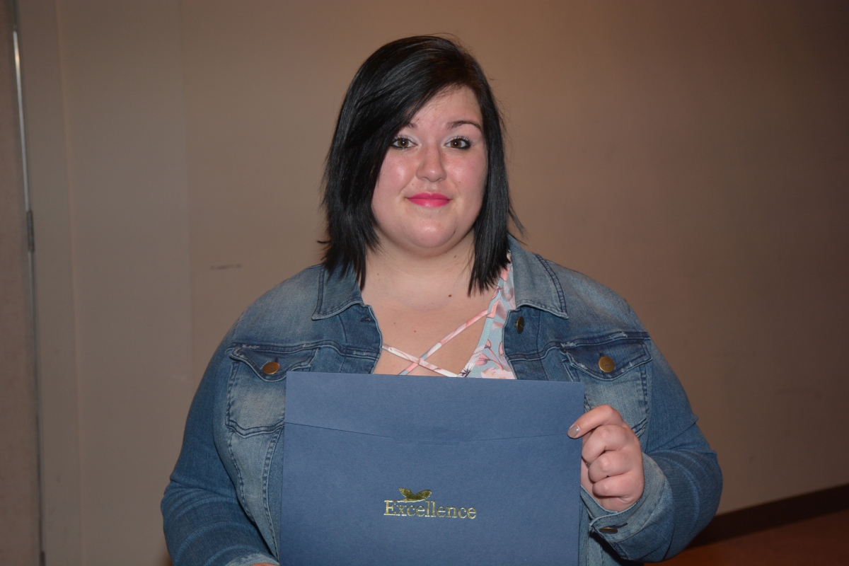 Female student holds award certificate.