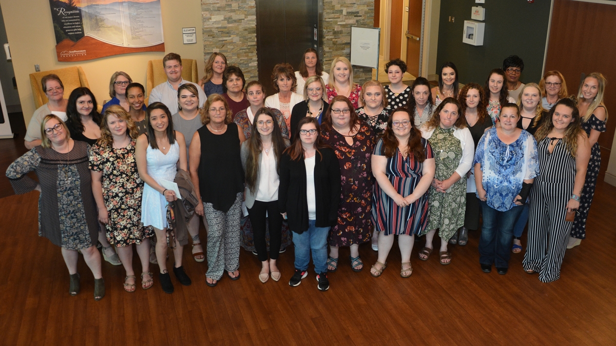 A large group of students stand with their instructors inside a building on SCC's Jackson Campus