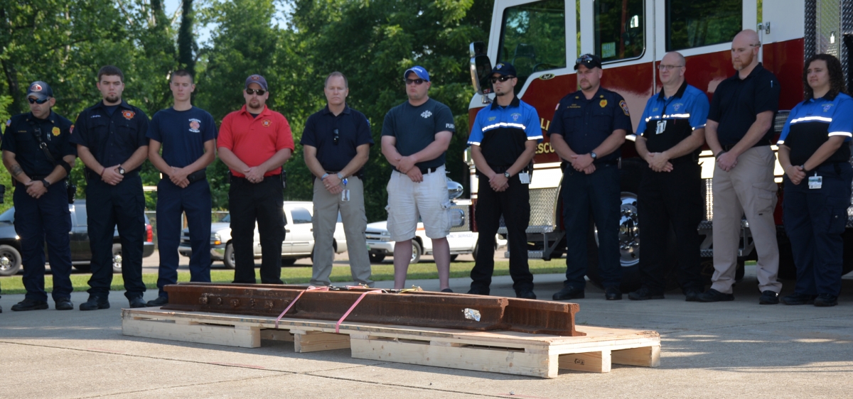 Photo of a line of first responders standing behind steel from the World Trade Center