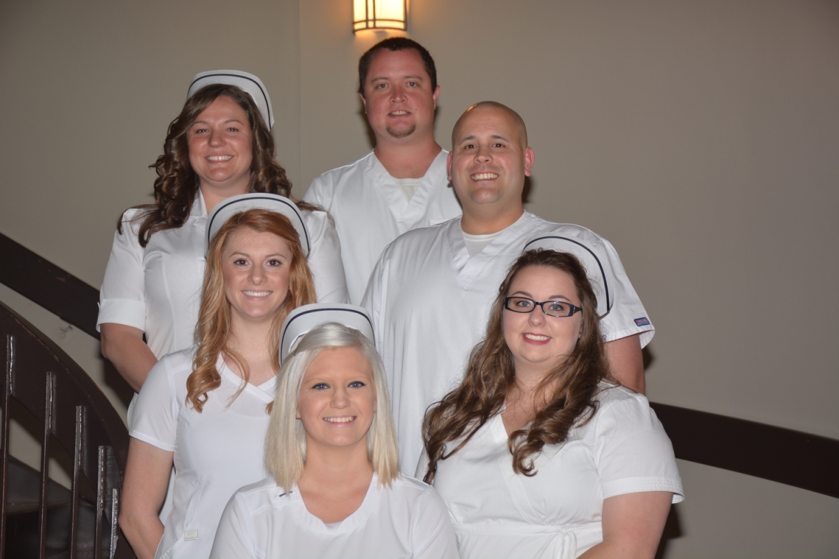 Six students standing in white attire smiling