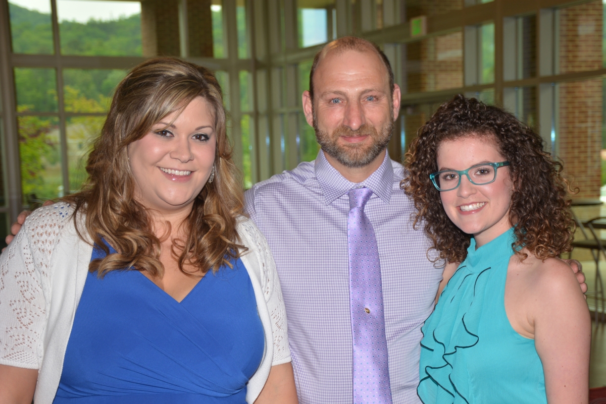 2 women and 1 man smiling at the camera