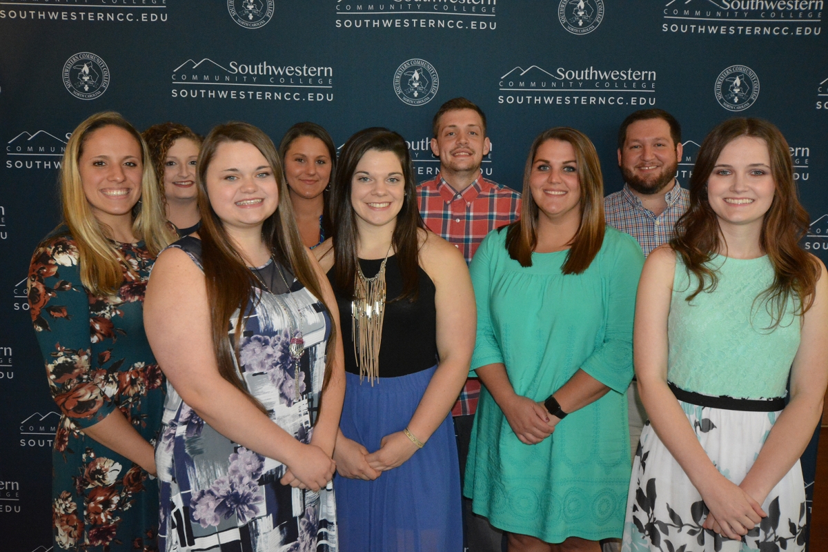 Group of students poses in front of a blue backdrop with SCC logo printed on it.