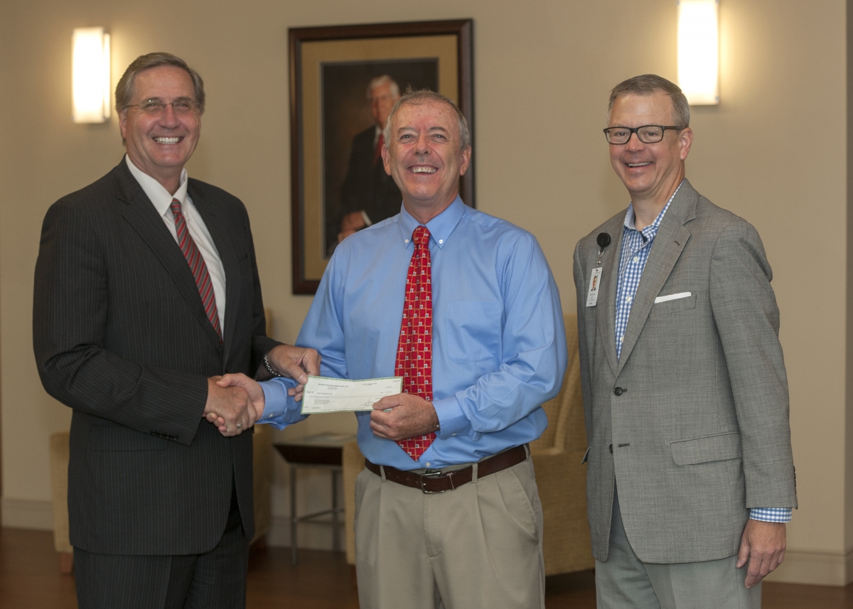 Three men pose during a check presentation inside a building on SCC's Jackson Campus
