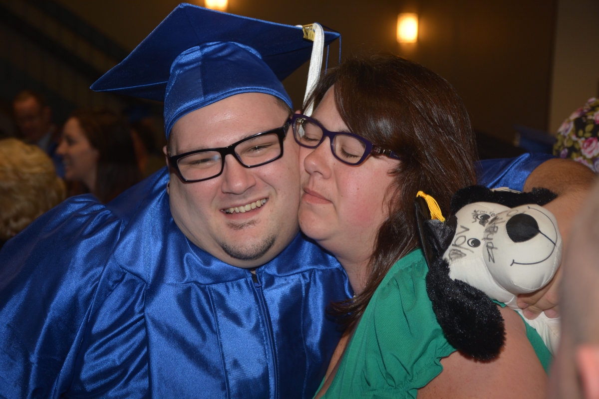 A male graduate gets a hug from a lady following the commencement ceremony in Sylva