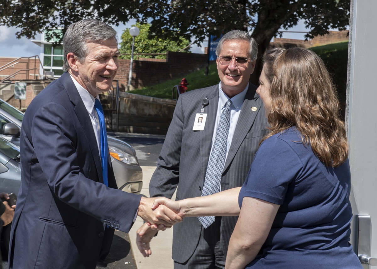 Governor shakes hands with an SCC employee as SCC president is in background.