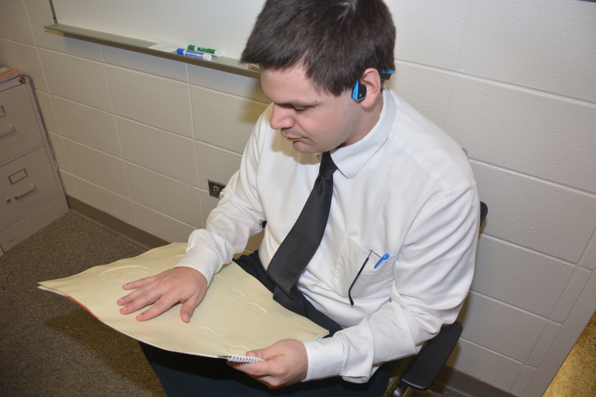 Man runs his fingers over braille in a book