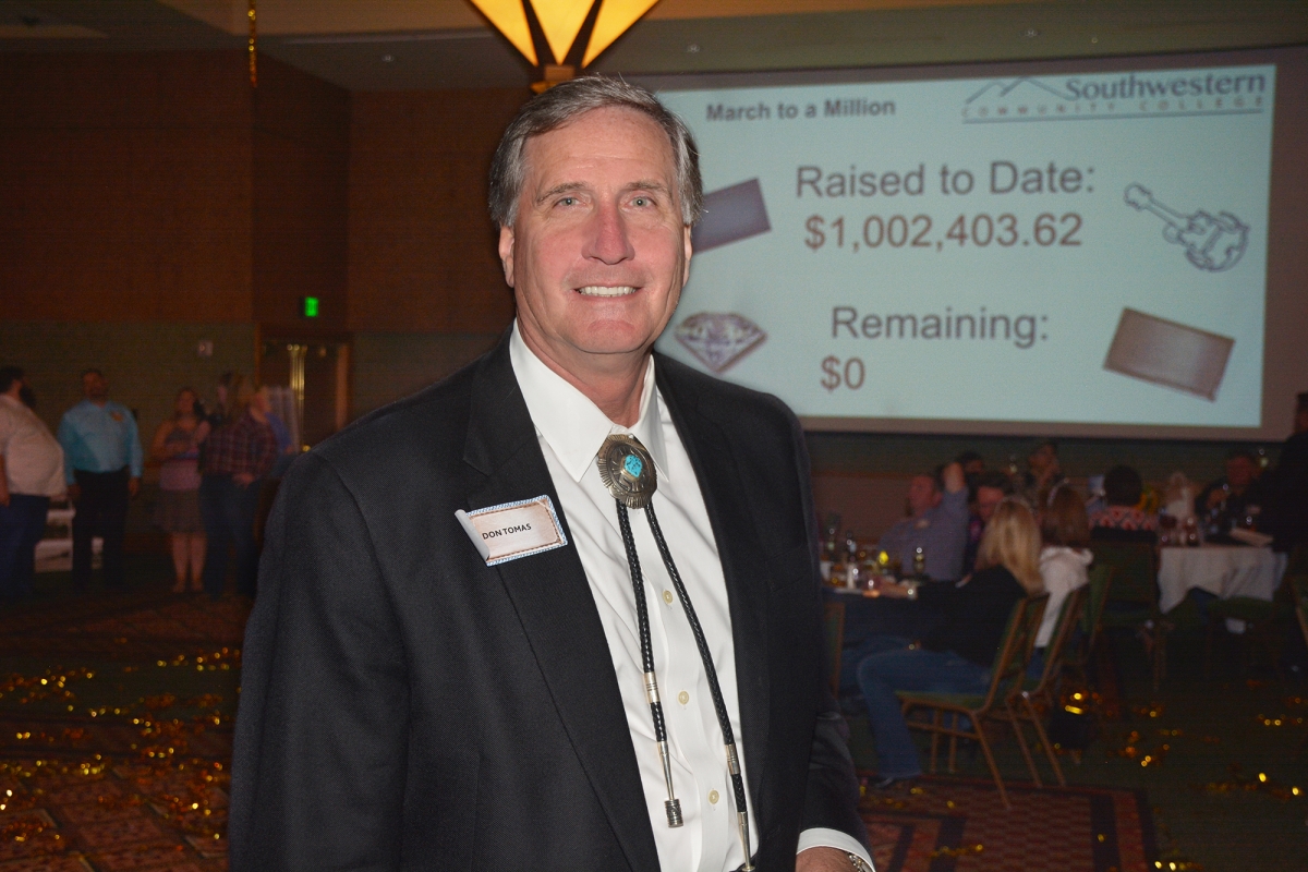 Man stands in front of a projector screen showing that SCC has reached $1 million for its endowment.