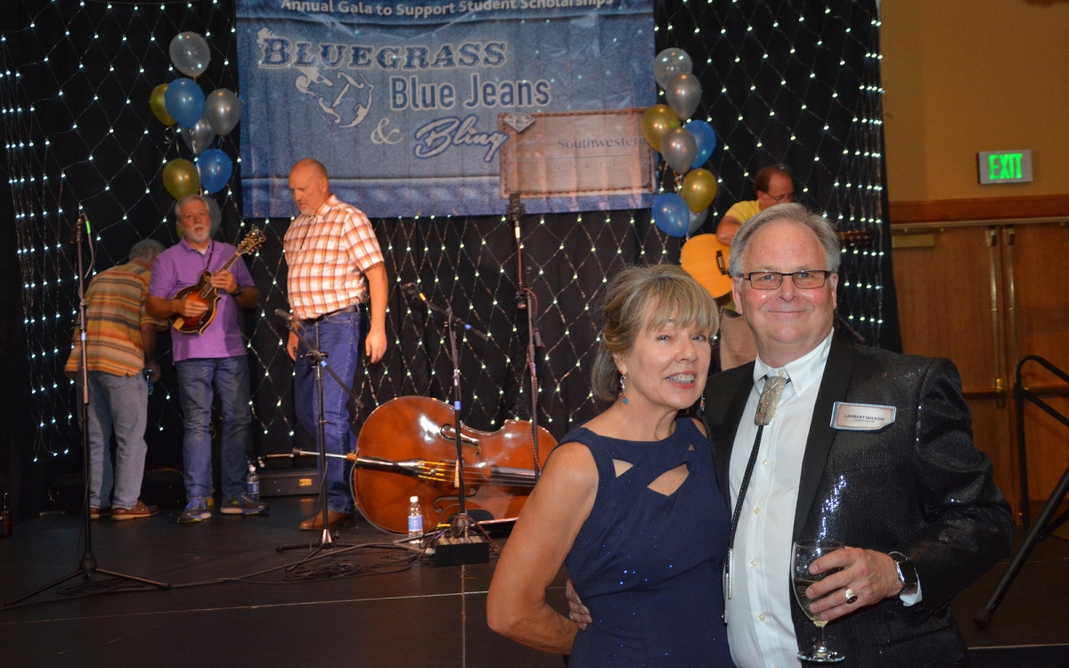 Man and woman pose for a photo in front of the stage inside the ballroom at Harrah's Cherokee Casino Resort
