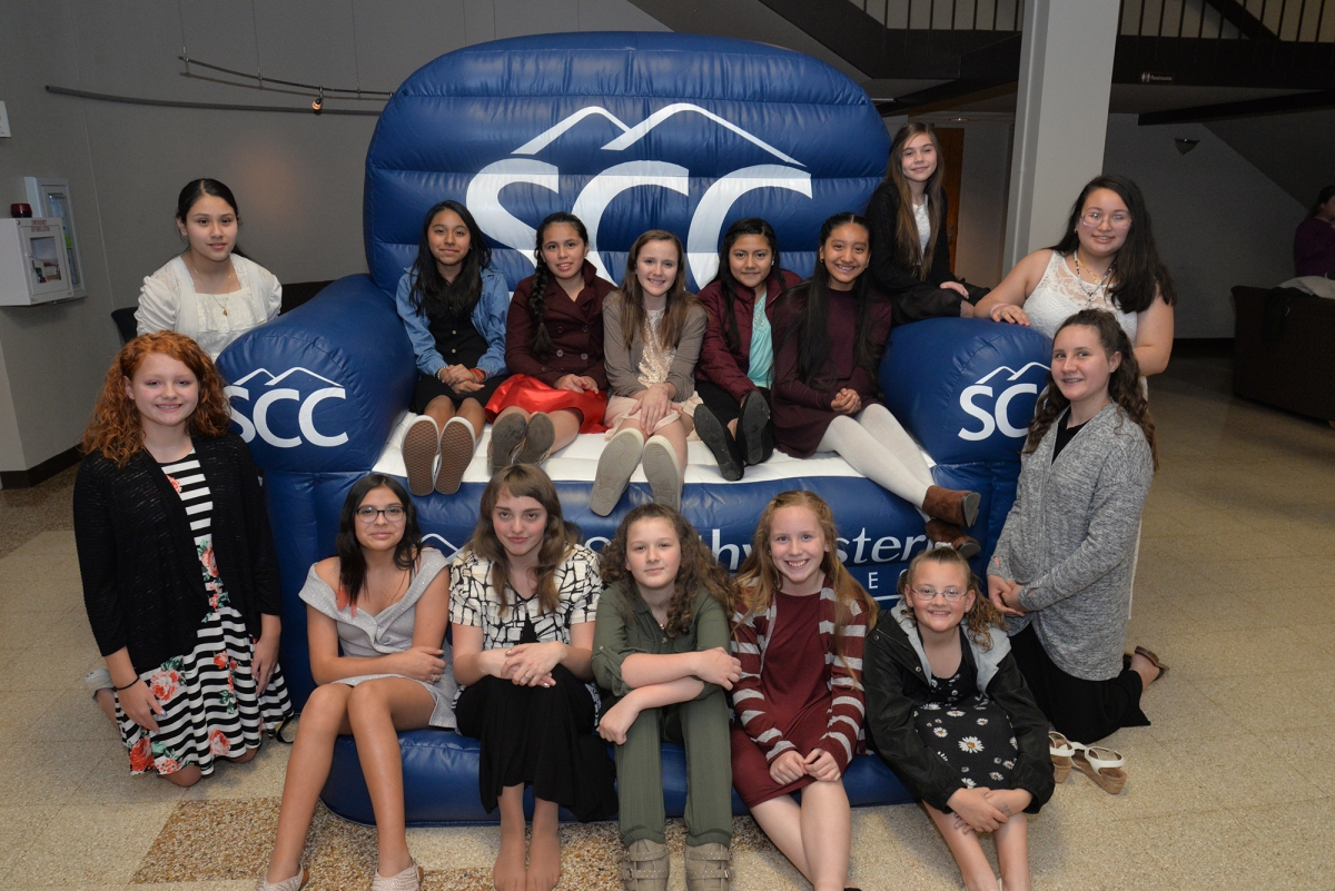 More than a dozen students pose on a blue inflatable chair with SCC logos.