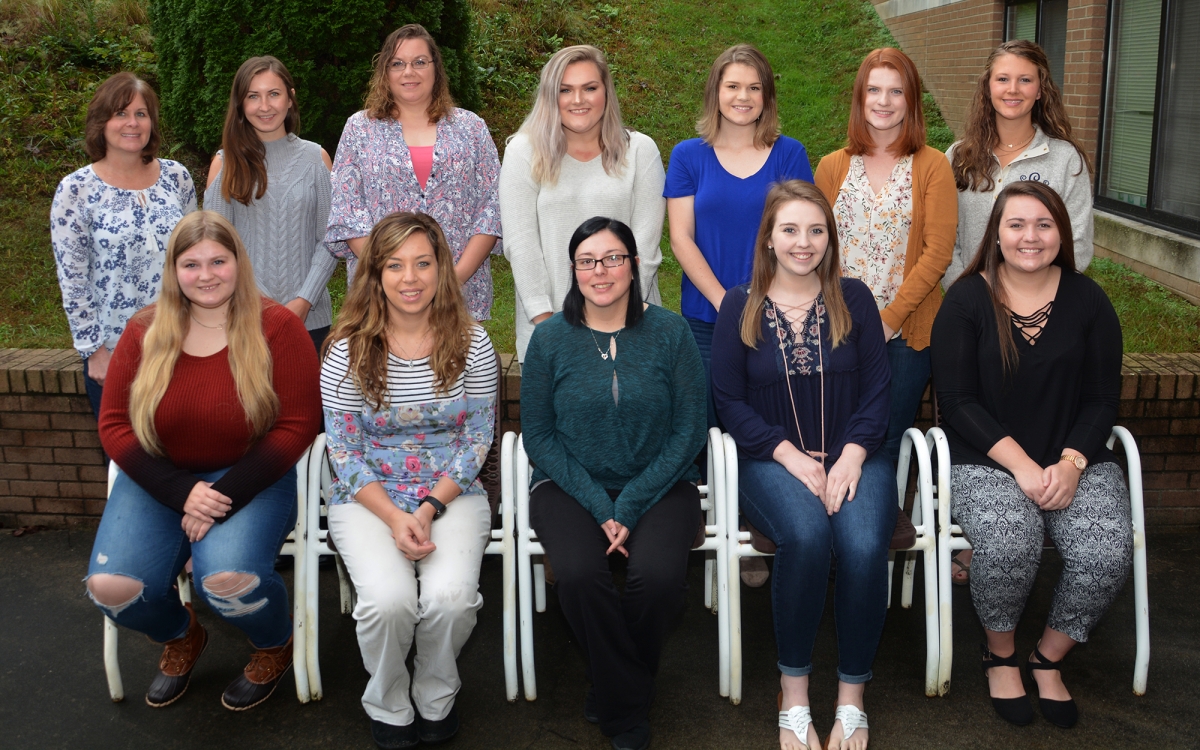 Two rows of young ladies pose outdoors on a fall day.