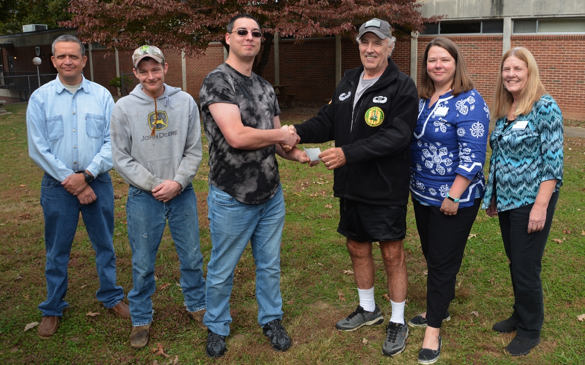 Four men and two women pose outdoors in autumn on SCC's campus in Sylva.