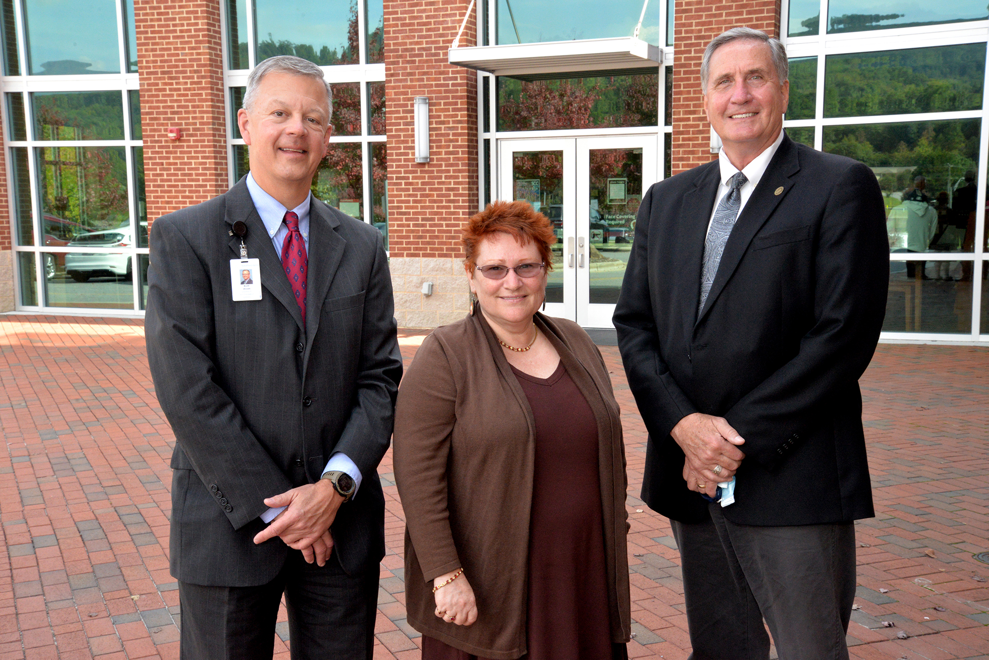 Woman stands beside two men outdoors