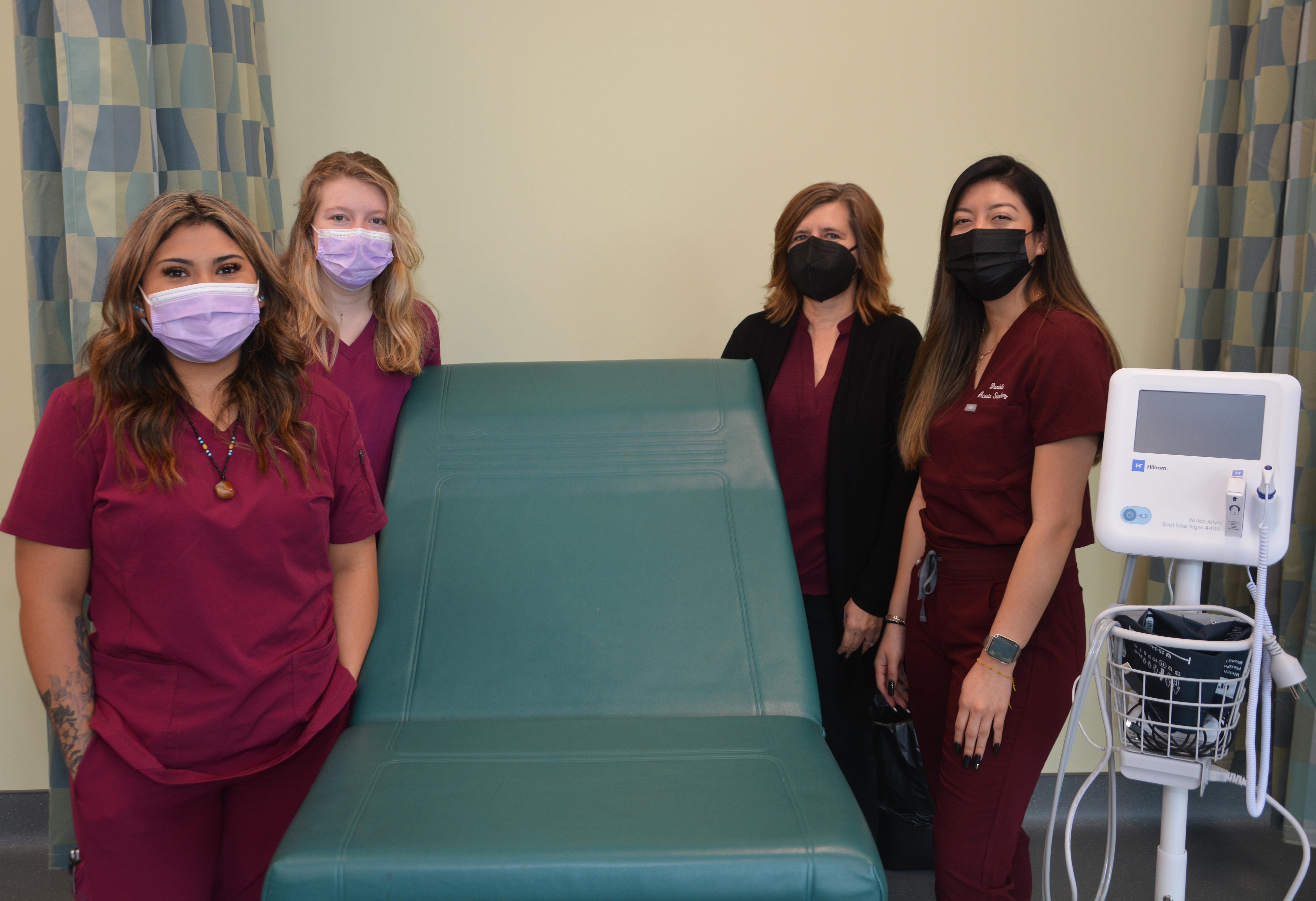 Three students stand beside their teacher, surrounding new equipment in their classroom.