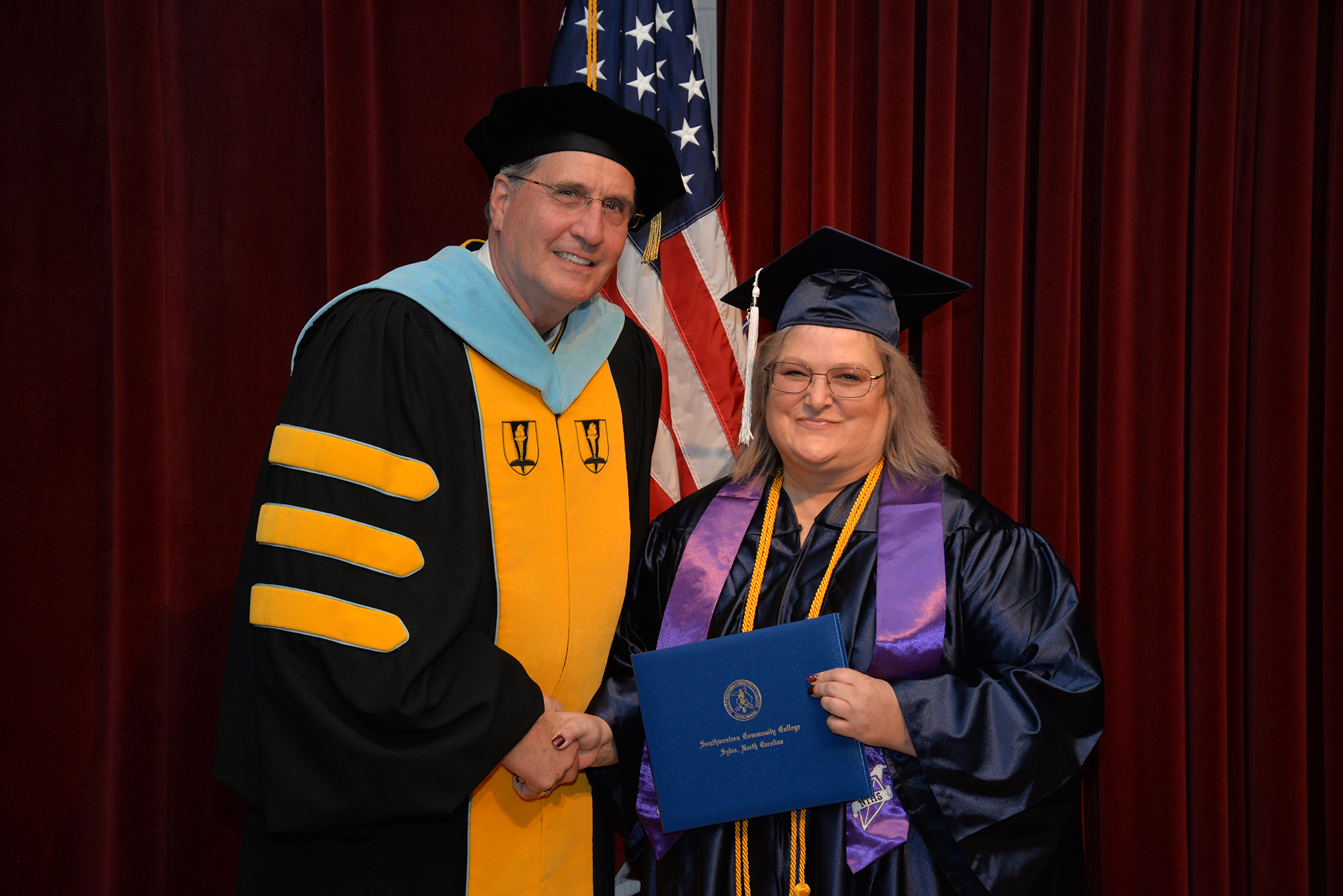 SCC President Dr. Don Tomas presents a diploma cover to a graduate in December of 2019, the last time Southwestern held a traditional indoor graduation ceremony