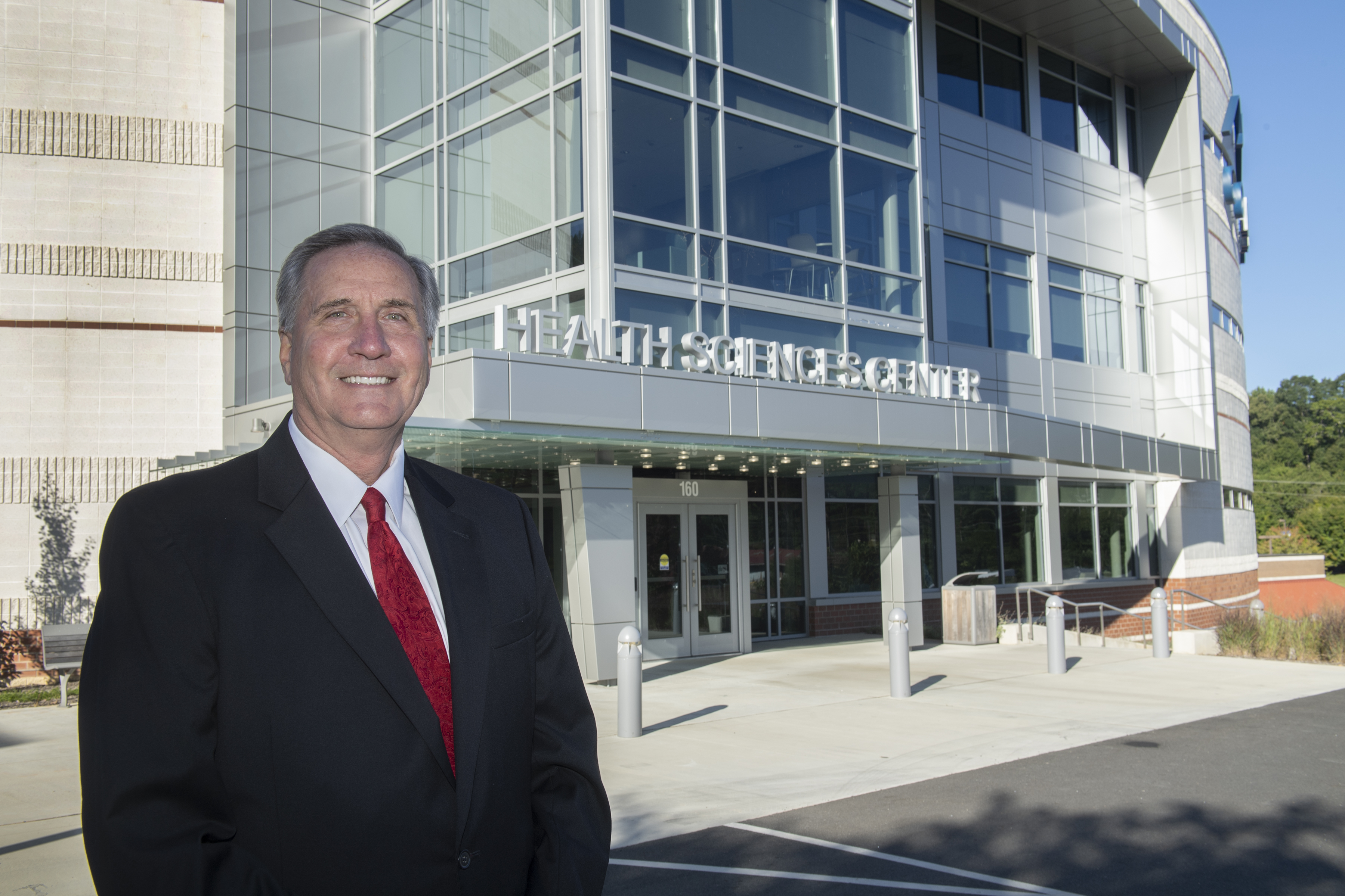 Don Tomas stands outside the Health Sciences Center that is being named after him