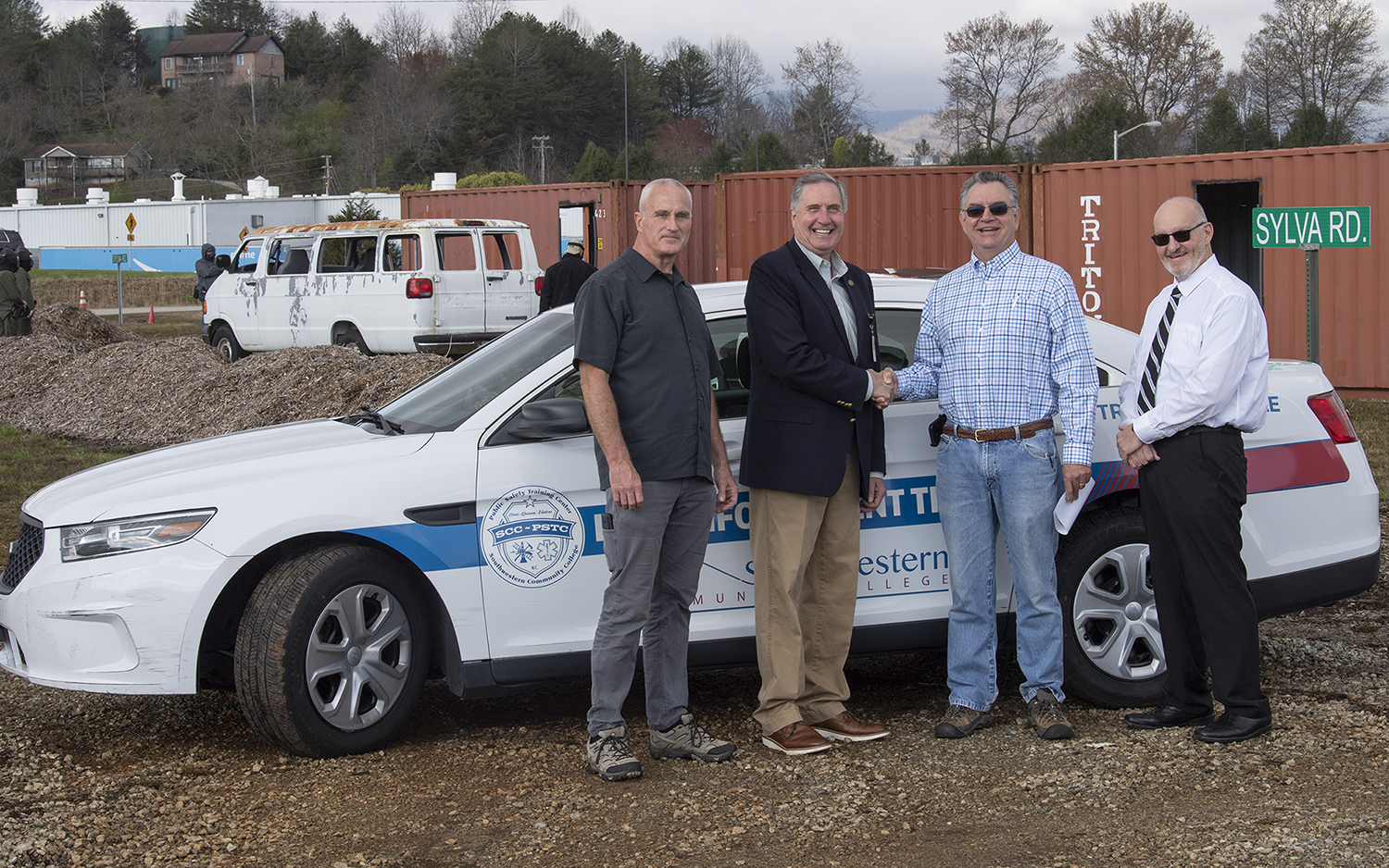 Four men stand in front of a public safety vehicle at the LEOUT