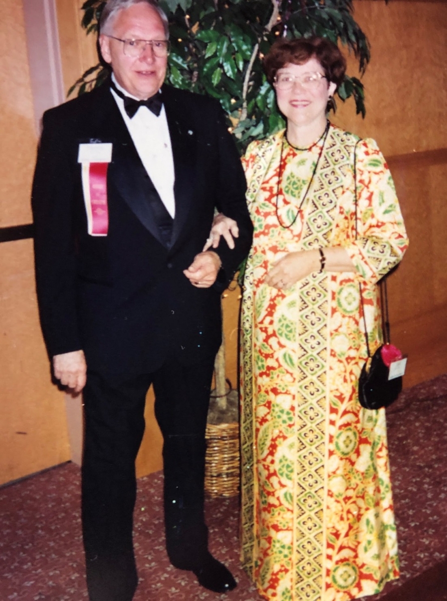 A man and woman stand together in formal dress