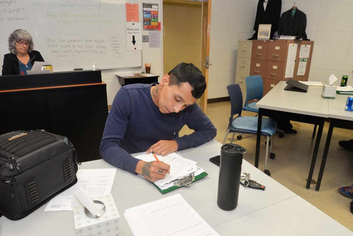 Young man bent over at a desk working hard on coursework. 