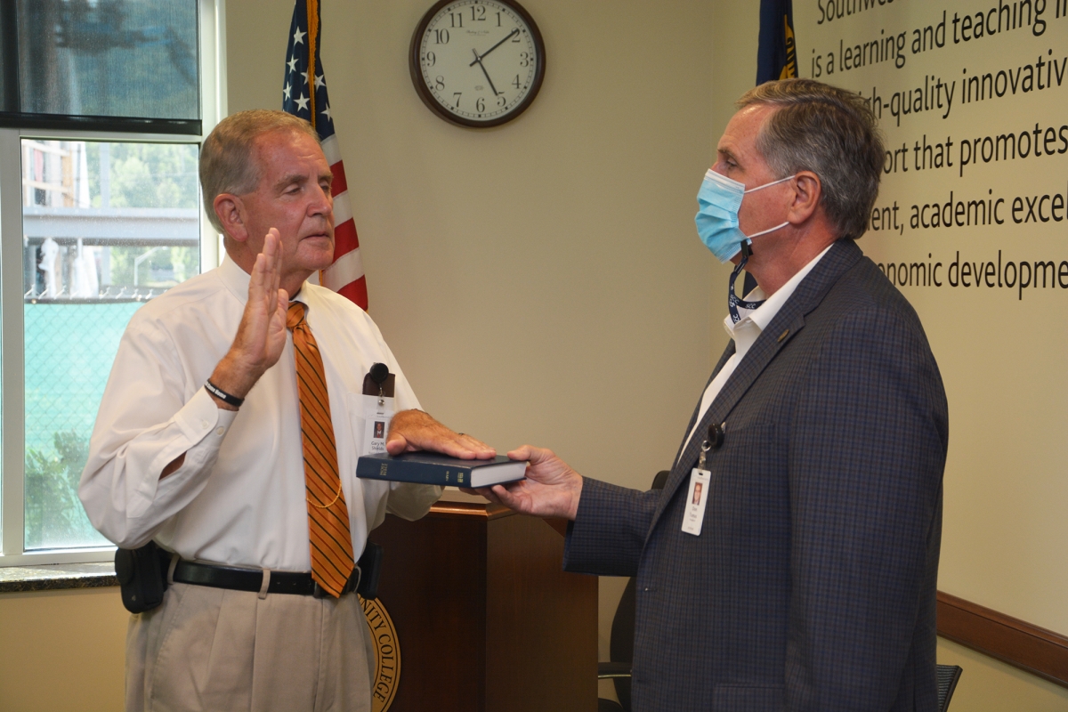 Two men place their hands on a bible