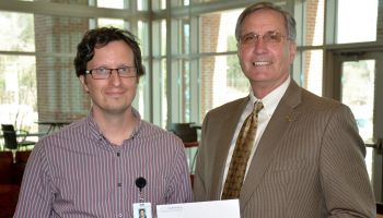 Two men exchange an envelope inside a building on SCC's Jackson Campus.