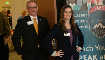 Man and woman stand at welcome table during a recent Job Fair.
