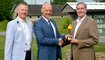 Three men pose outdoors for a photo.
