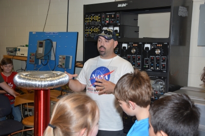 Man wearing NASA shirt shows middle school students a Tesla Coil