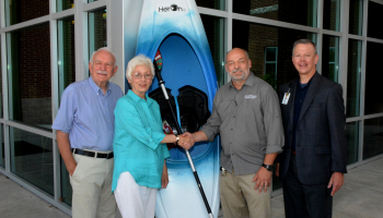 Three men and a woman stand beside a kayak outside a building on SCC's Jackson Campus in Sylva.